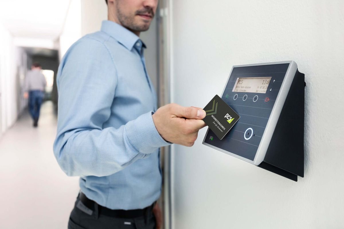 Employee presenting an RFID badge to an electronic wall-mounted access reader.