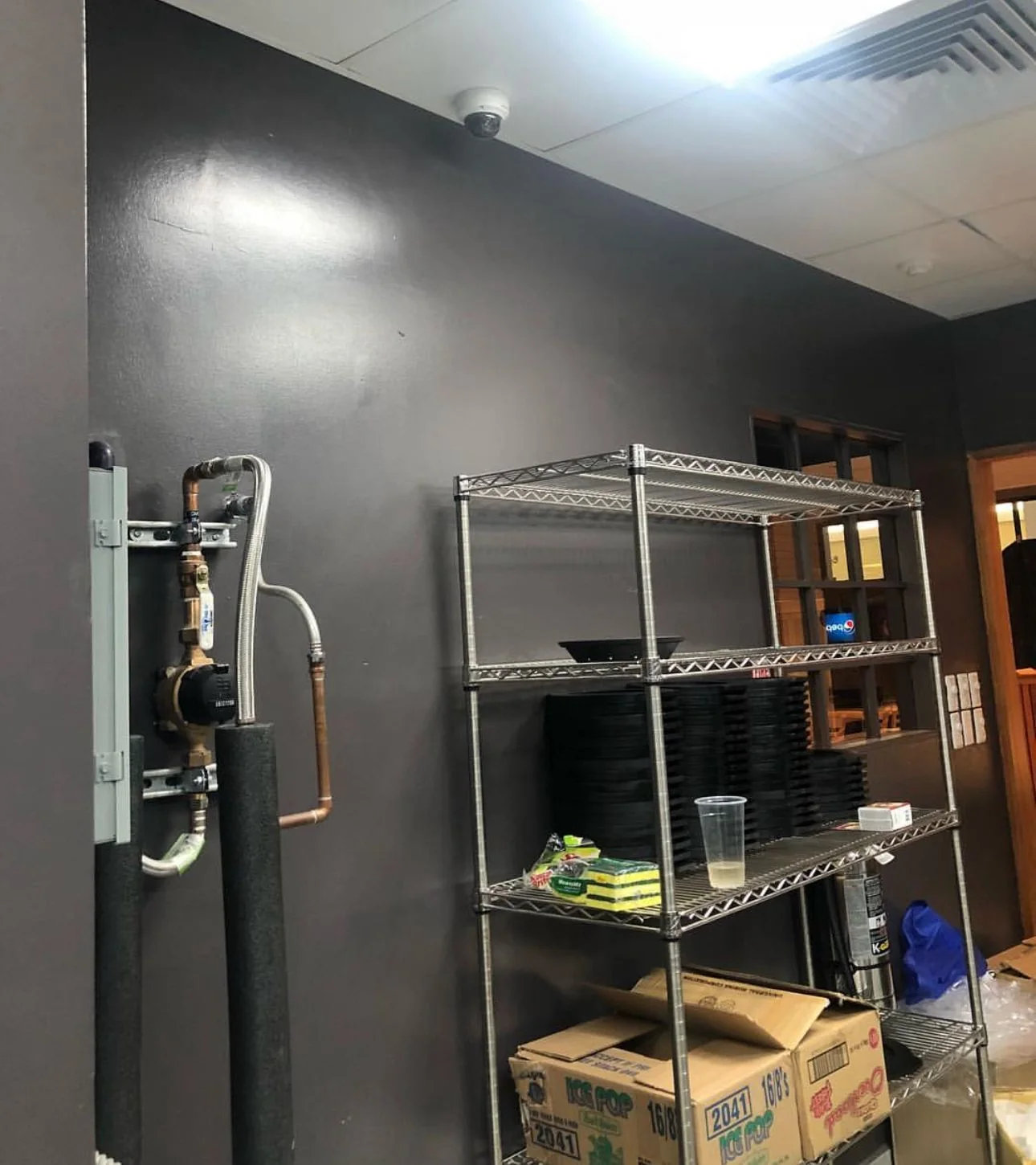 Ceiling surveillance camera positioned above metal shelving in a storage room.