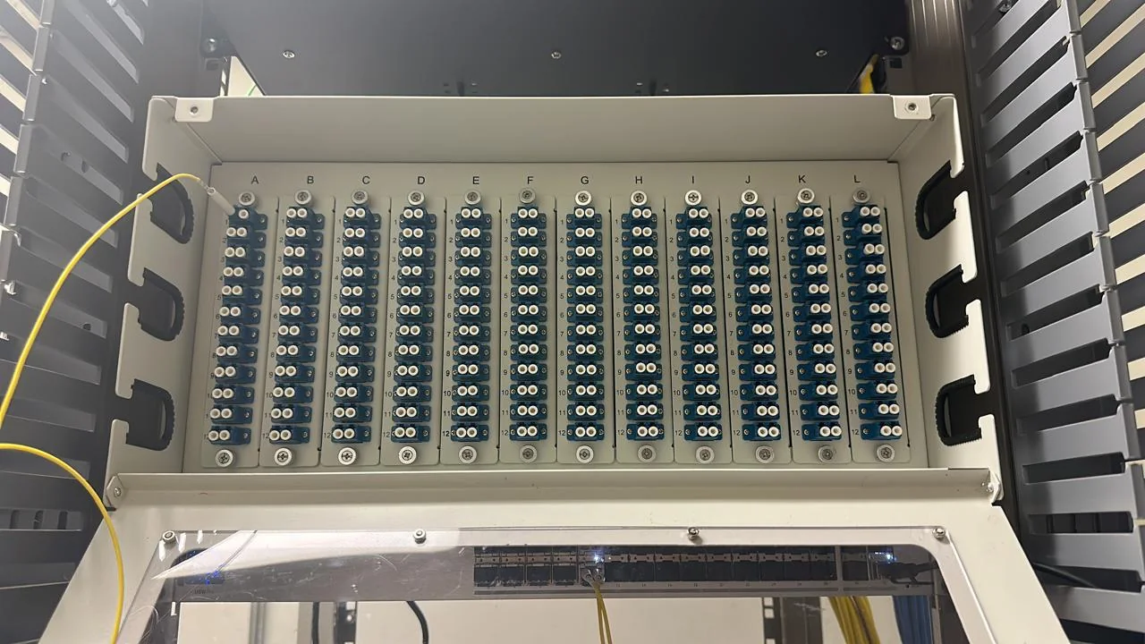 Fiber distribution panel with rows of blue adapter ports mounted inside a telecommunications rack.