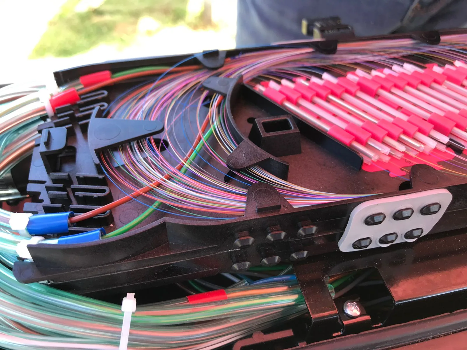 Colored fibers routed around a splice tray and into protective sleeve holders.