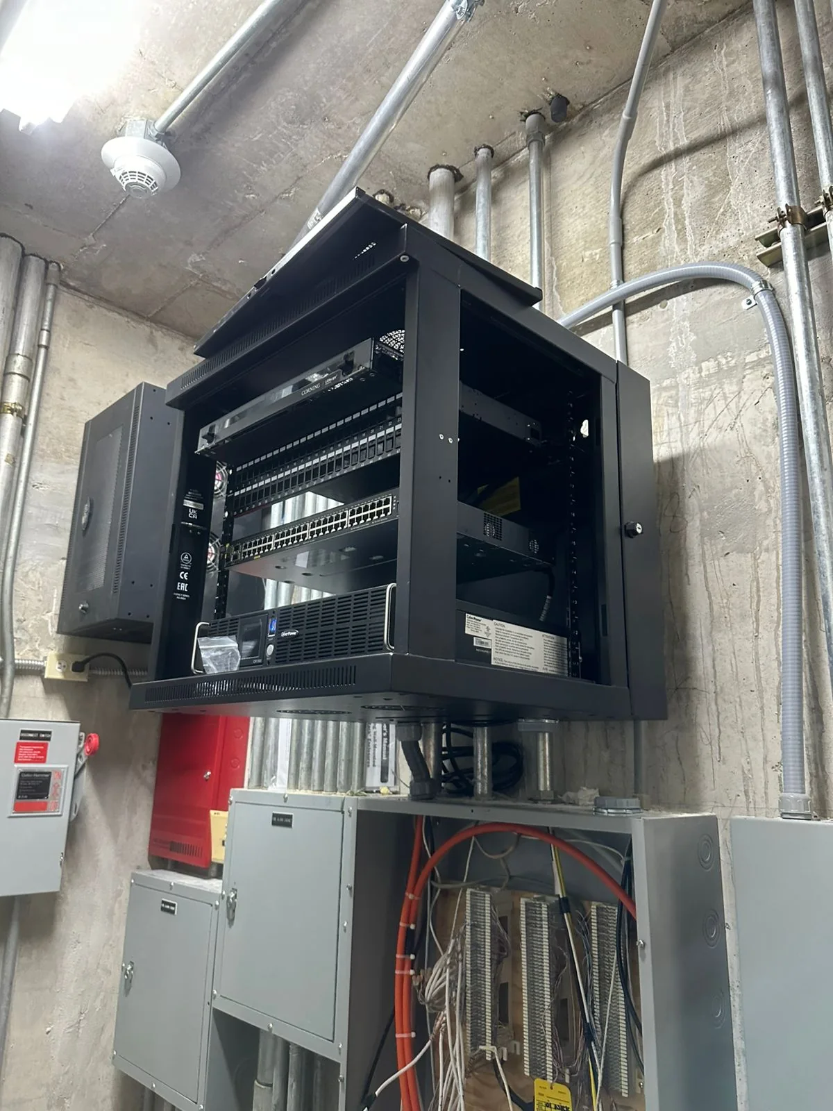 Open wall-mounted network rack with a switch, patch panels, and connected cabling.