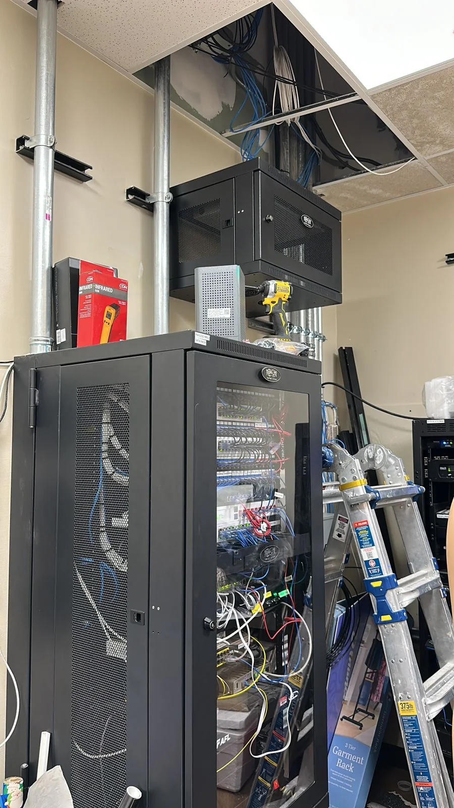 Floor-standing network rack and wall-mounted patch-panel cabinet in a communications room.