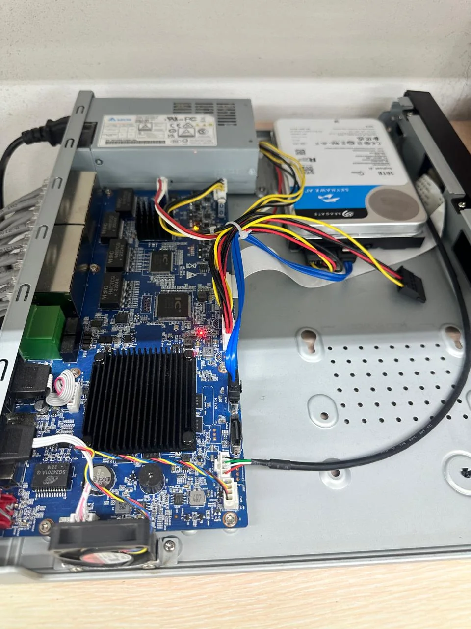 Overview of an open surveillance recorder with a circuit board, hard drive, power supply, and wiring.