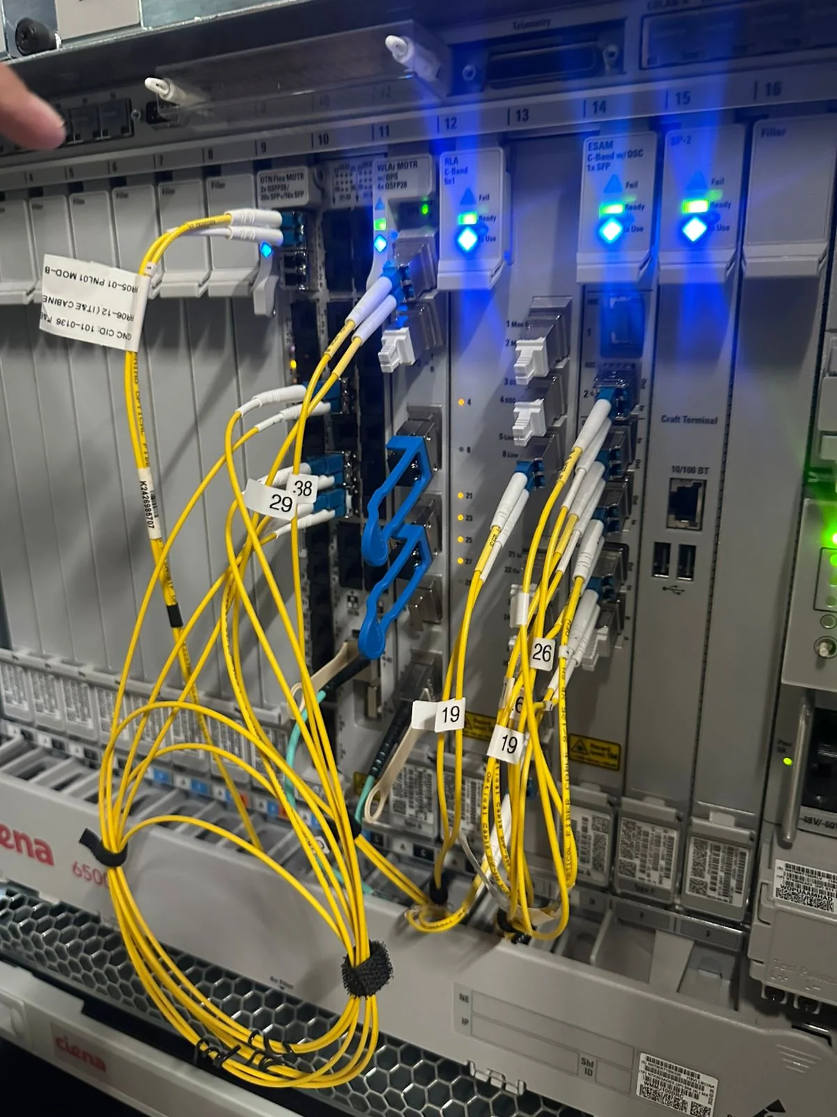 Rack-mounted optical transport equipment connected with yellow fiber patch cables.