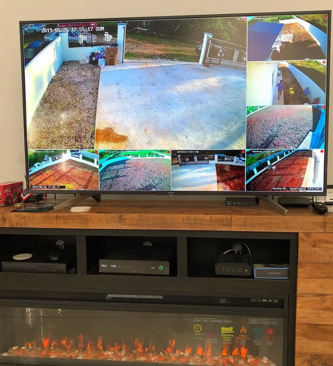 Indoor television displaying a grid of exterior surveillance camera views above recording equipment.