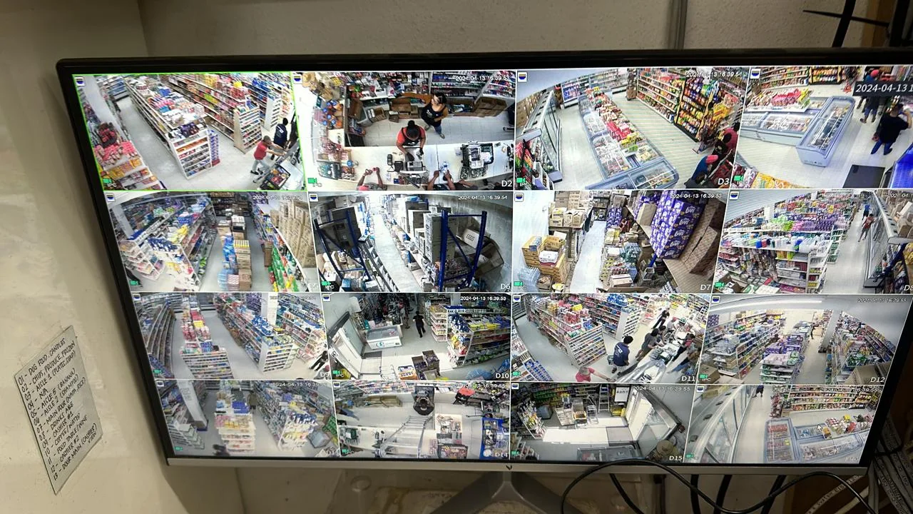 Wider view of a surveillance display showing multiple retail camera feeds with surrounding display equipment.