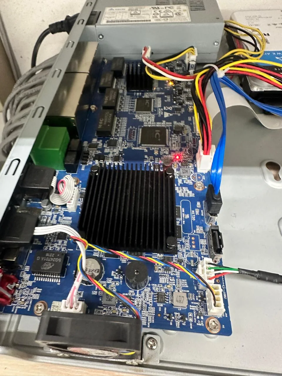Open surveillance recorder chassis showing its circuit board, cooling heatsink, power supply, and internal connections.