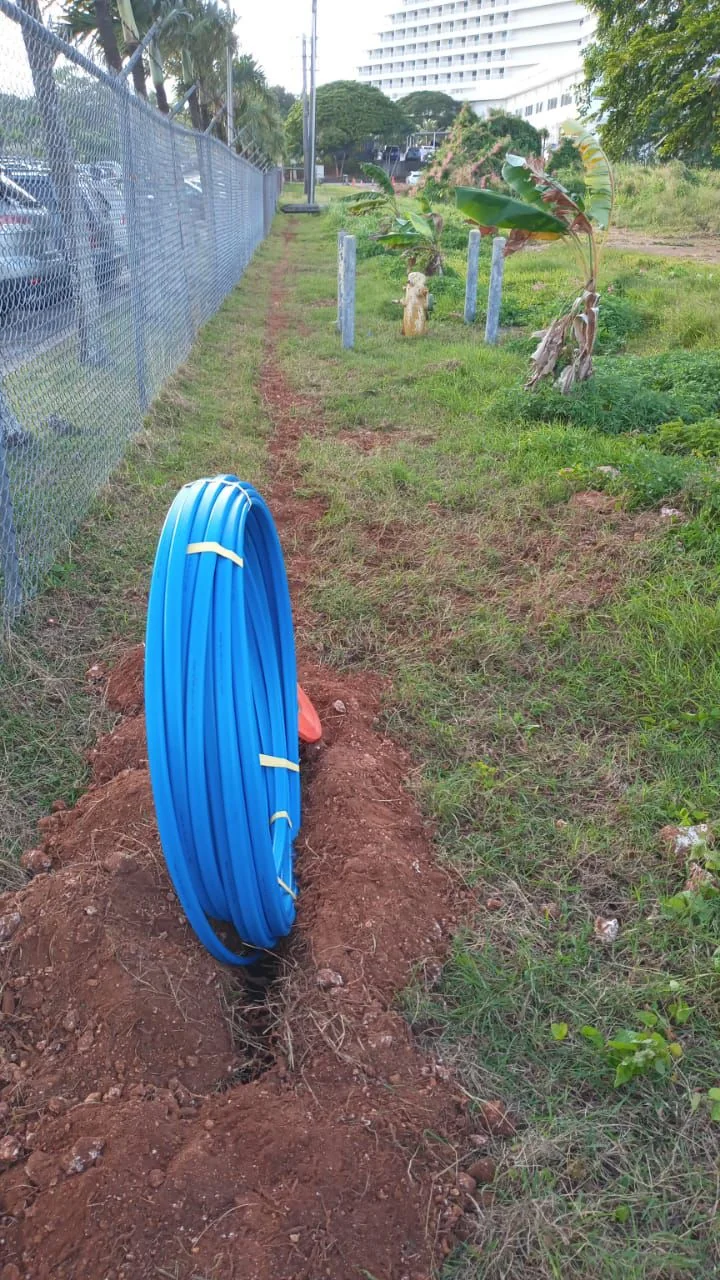 Blue conduit coil beside a narrow excavated soil pathway.